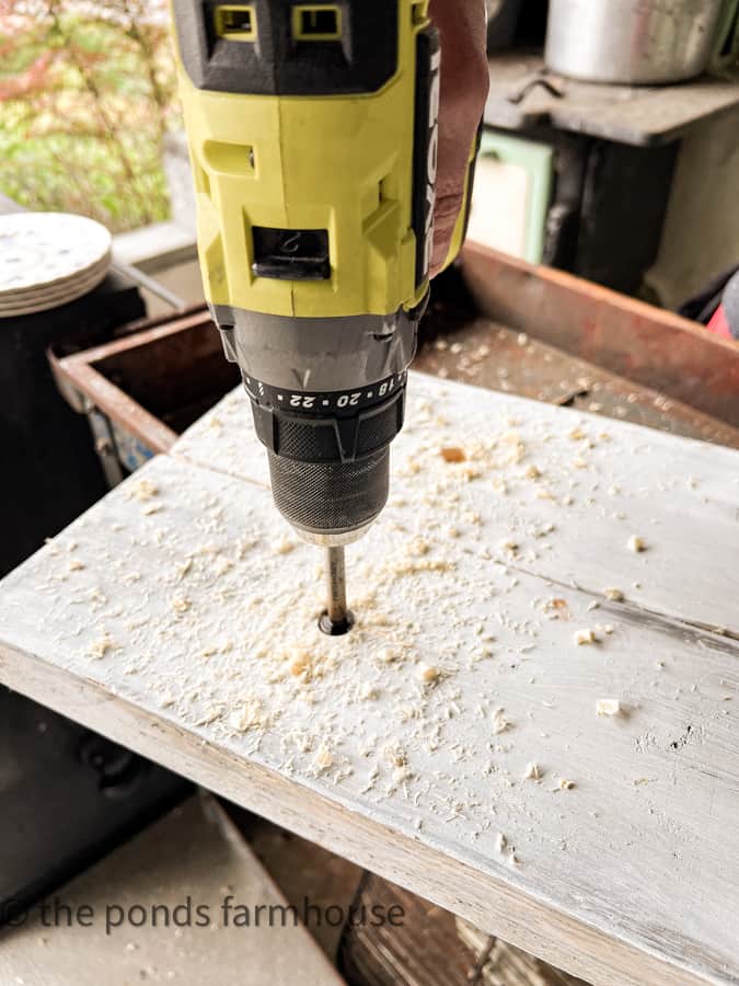 Holes being counter sunk for screw for knobs on rustic kitchen cabinet.