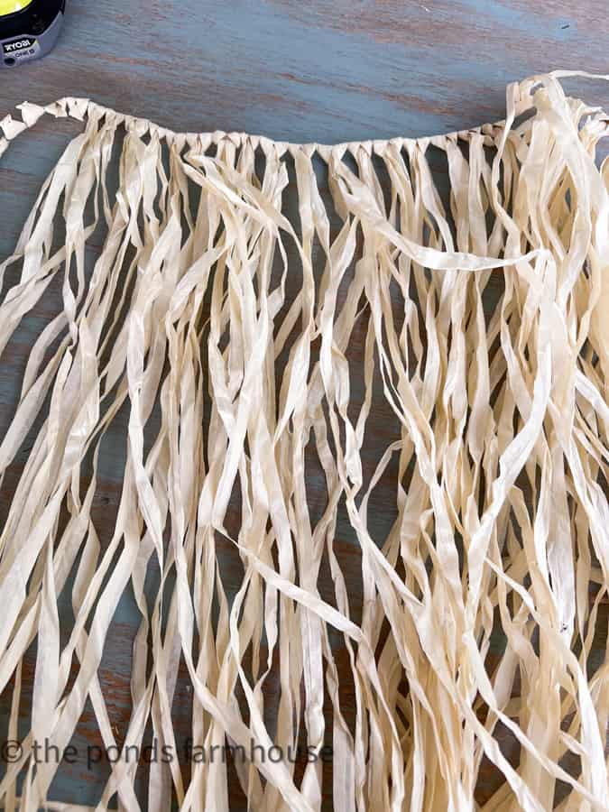 Use a Dollar Tree grass skirt for cheap napkin rings pom poms.  
