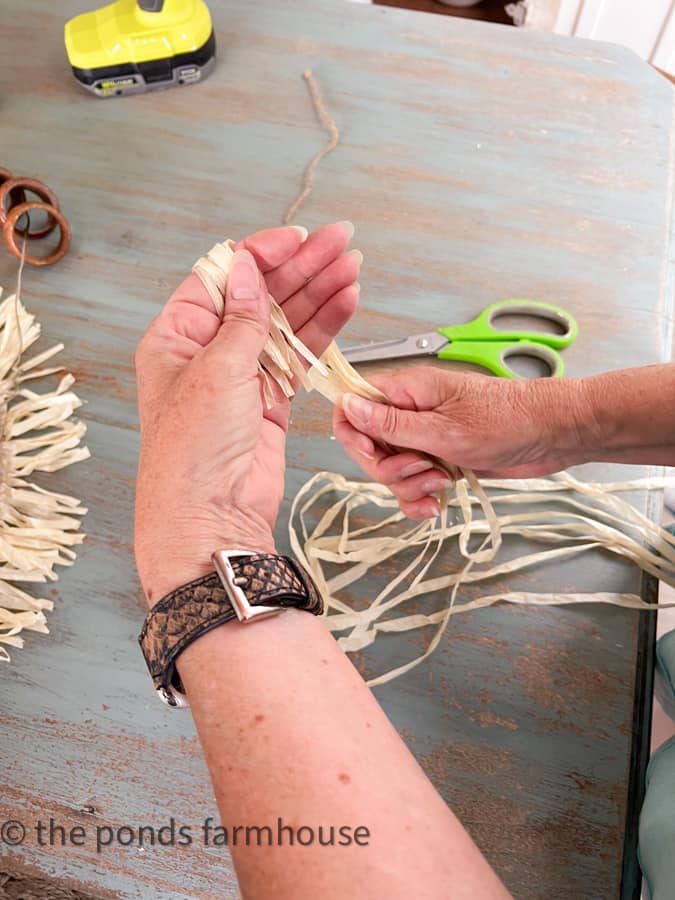 Wrap raffia around fingers to make  straw pom poms to add to the thrift store rings.