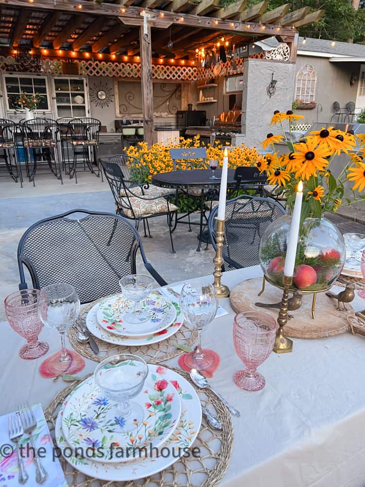 Supper Club Summer Tablescape with floral dishes and pink glasses.  Black Eyed Susan and Fresh Peach Centerpiece