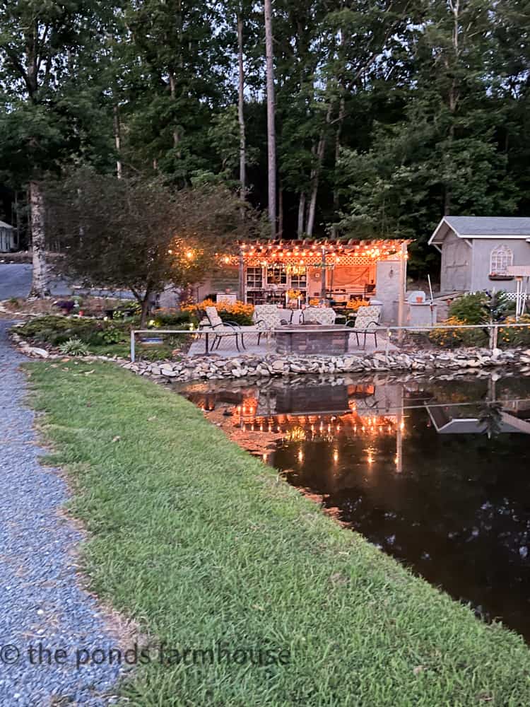 Outdoor kitchen with fire pit in front of a pond with twinkle lights for evening Peachy Keen Dinner Party