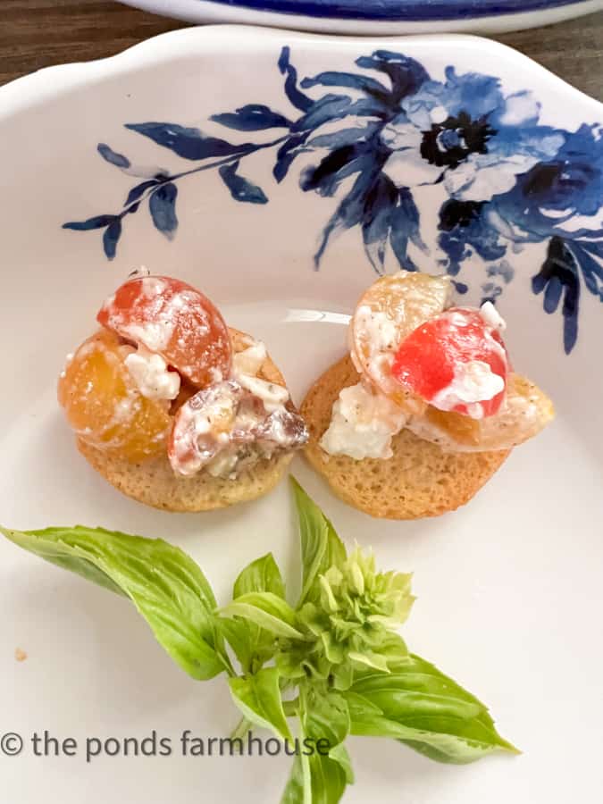 Tangy Tomato Greek Dip with feta appetizer on toasted bagel bites and fresh basil garnish. 