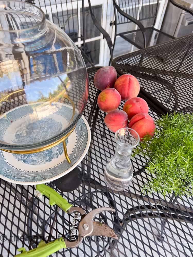 Peaches, fern and glass vessels to make a fruit and flower centerpiece