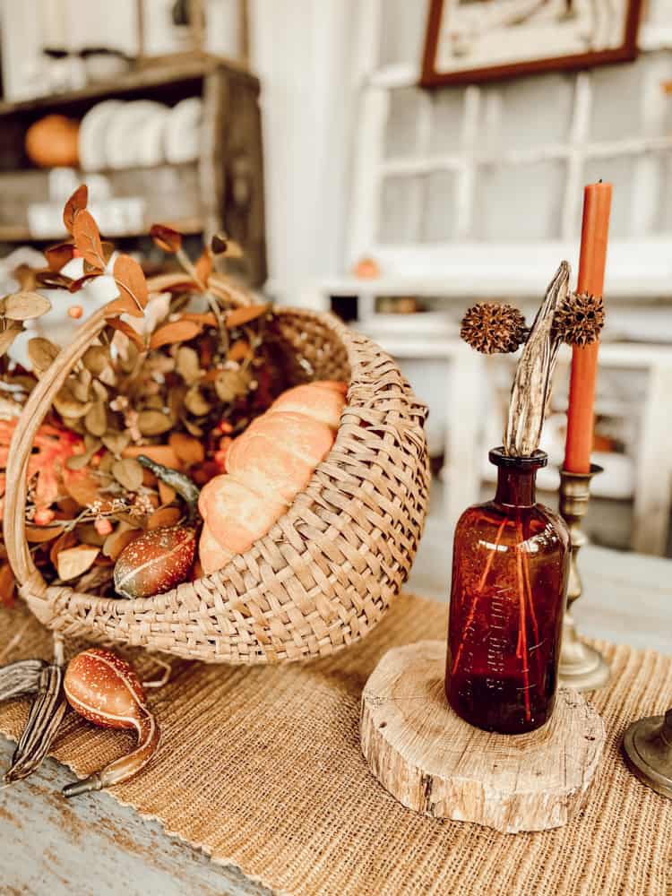 old bottle with dried okra and sweet gum balls and basket centerpiece for vintage fall decor.