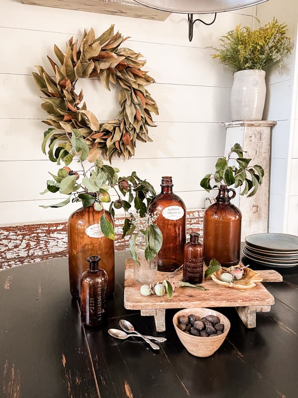 DIY magnolia wreath with wildflowers in a vintage crock and Amber bottles filled with foraged persimmons.