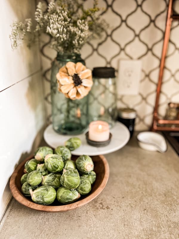 Brussel Sprouts in wooden bowl with blue mason jar and pinecone sunflower for Cheap Autumn Decor