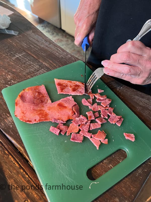 Chop country ham with a knife on a cutting board.