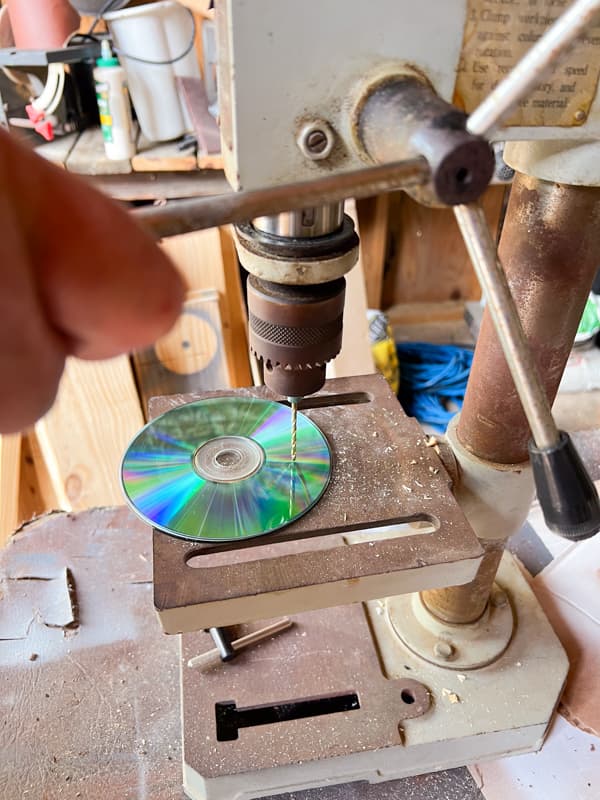 Use drill press to make holes in CDs.