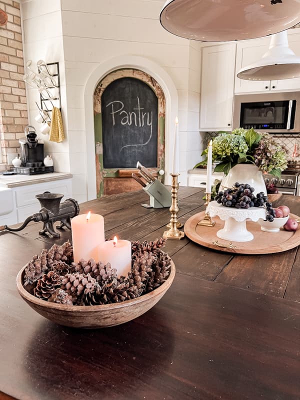 Foraged pinecones in wooden bowl with candles on kitchen island for Cheap fall decor and Autumn Decor.