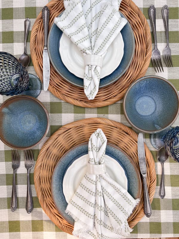 Blue earthenware pottery dishes on woven thrifted placemats for a potluck dinner party.  Origin of potluck