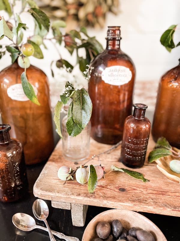 Vintage and antique amber bottles for a country chic rustic farmhouse table centerpiece with foraged persimmons.