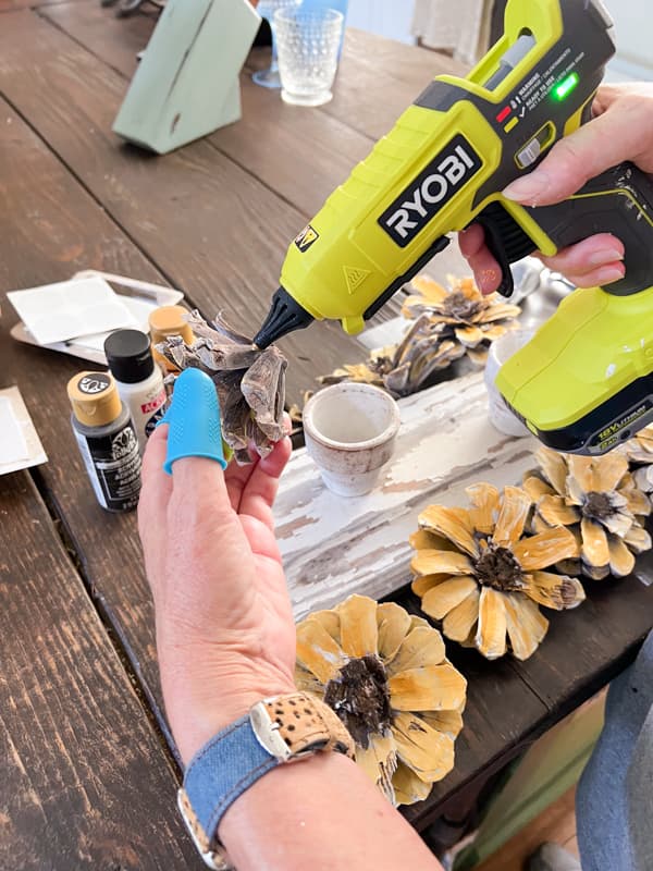 Use hot glue gun to attach pinecone sunflowers to the reclaimed shiplap wood.  
