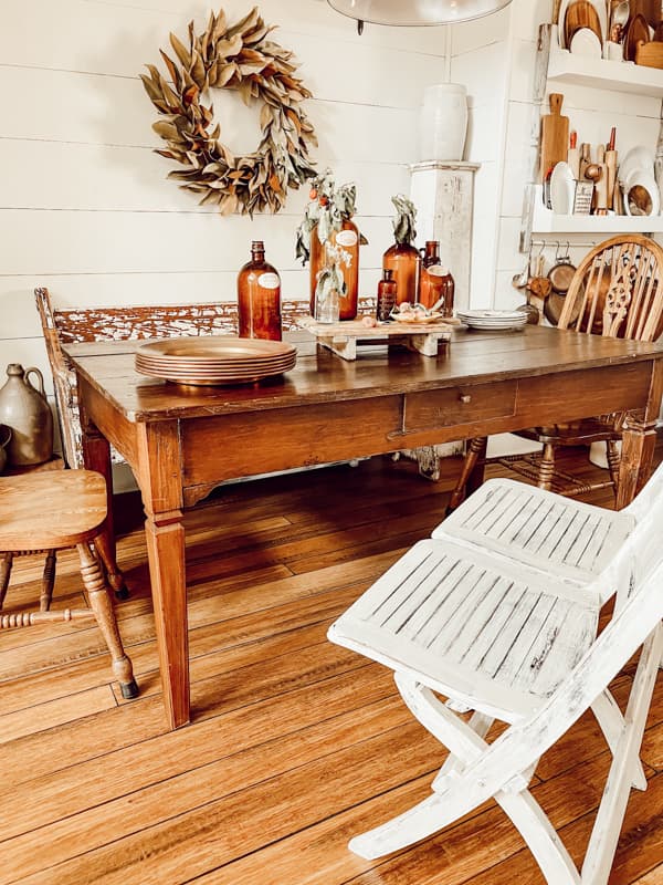 Vintage dining table with copper plate chargers and vintage brown bottles.