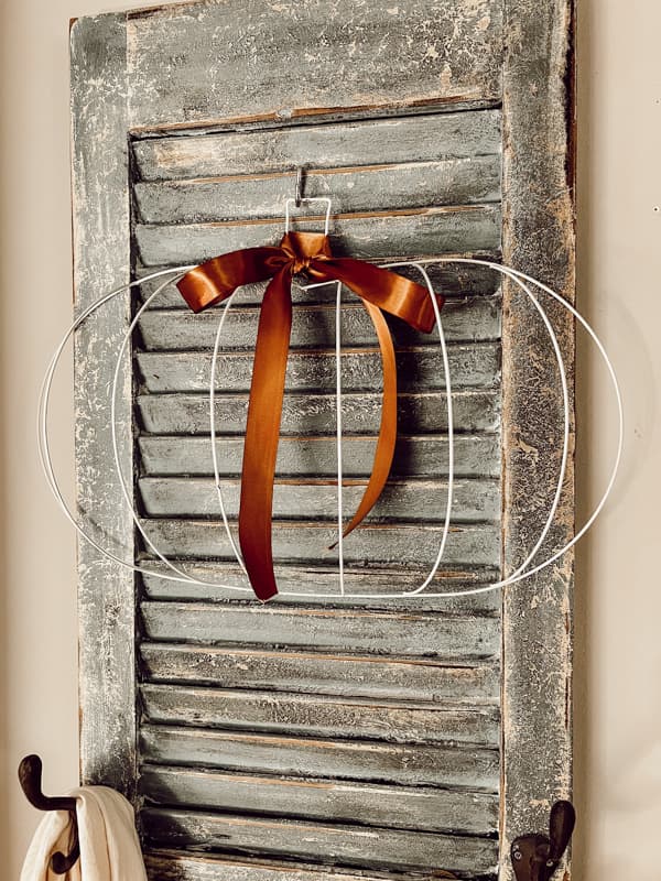 Pumpkin with ribbon on vintage shutter for farmhouse style fall decor that is budget-friendly.