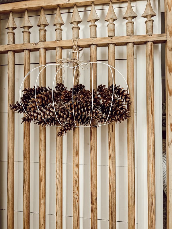 DIY Dollar Tree pumpkin with foraged pine combs hanging on vintage door. Fall crafted pumpkin.