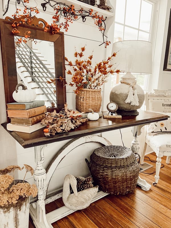 Side table with fall decor. Vintage basket, vintage books, pottery barn lamp dupe.