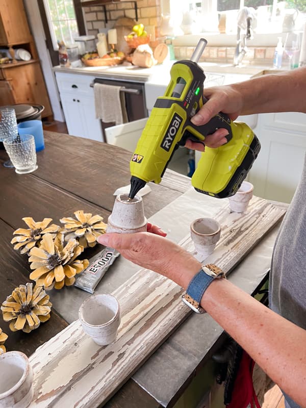 Add hot glue to bottom of clay pots for sunflower centerpiece craft.  