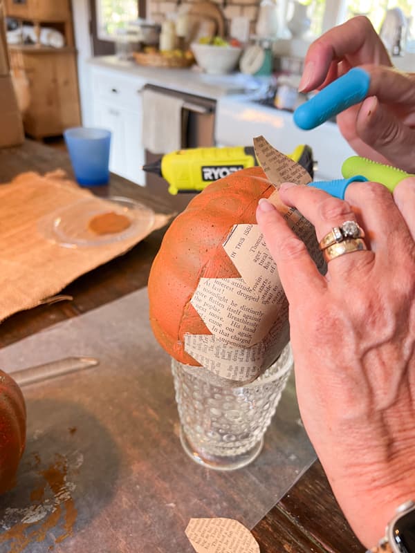 Use hot glue to add teardrop sharped old book pages to Dollar Tree Pumpkin for Pumpkin Craft.