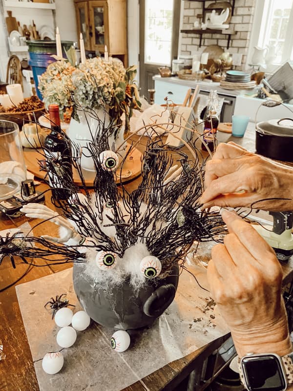 Add spiders with hot glue to make a DIY Halloween Centerpiece with Dollar Tree DIY Centerpiece Decor.