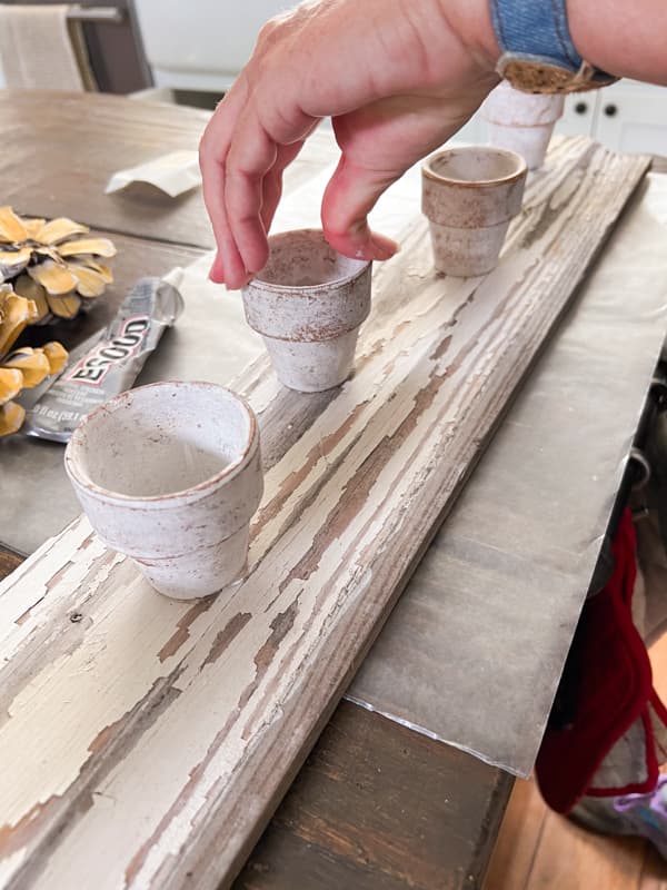 Attach clay pots to the reclaimed shiplap board for DIY Fall Centerpiece and cottage-core handcrafted art.