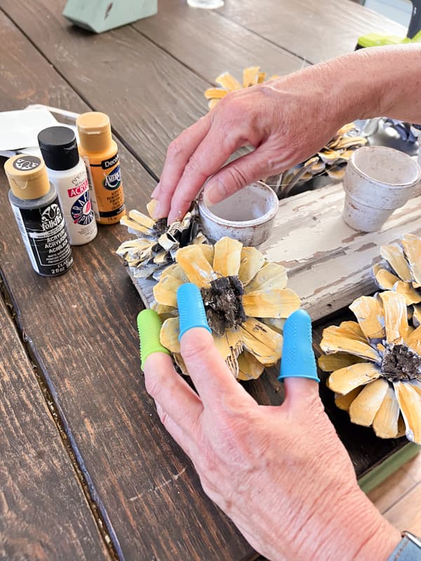 Hold sunflowers in place until they dry and adhere to the wooden board.  