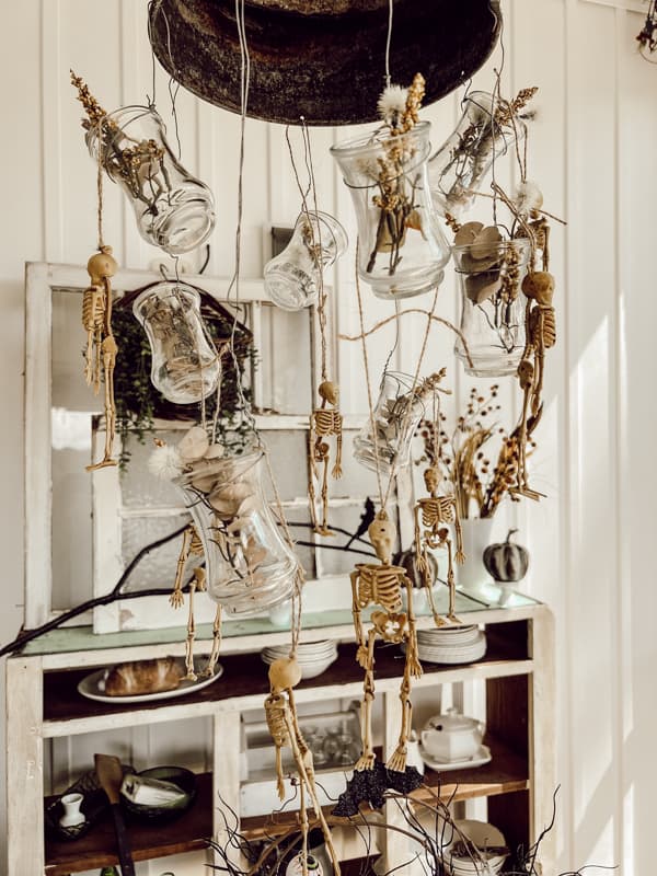 Dollar Tree Skeletons on DIY light fixture over Halloween table setting.