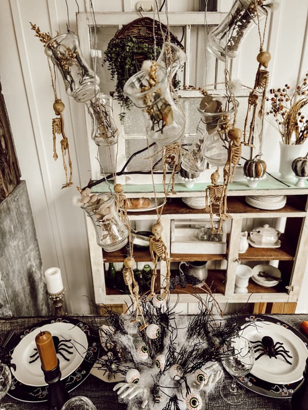 Dollar Tree Skeletons on DIY light fixture over Halloween table setting.