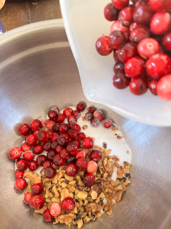 Pour cranberries and walnuts to toss with flour and sugar for a Holiday Dessert Recipe