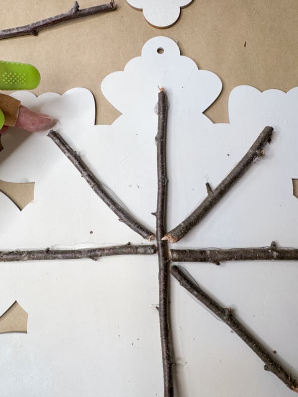 adding foraged twigs to wood cutout snowflake