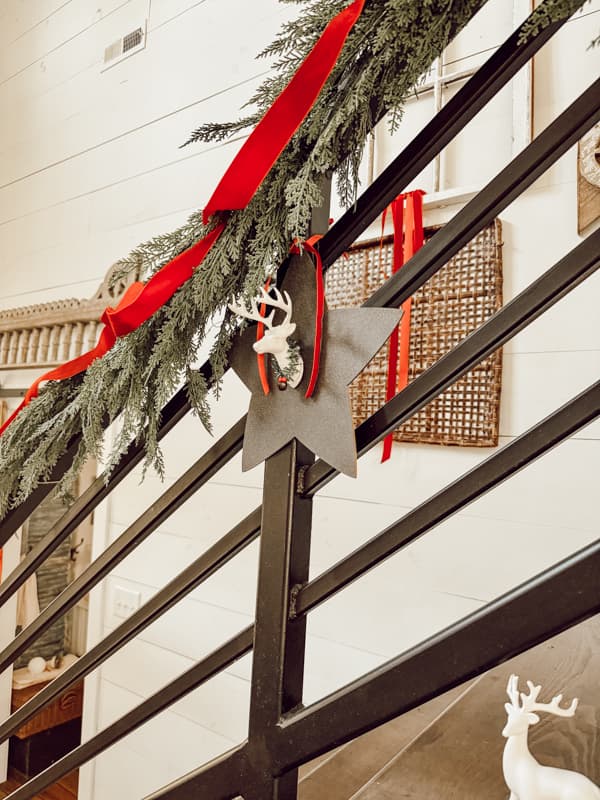 add DIY large Christmas ornaments to greenery garland for decorating a large banister this holiday