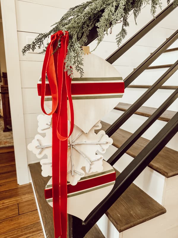 three DIY large Christmaa ornaments with red velvet ribbon at the end of the banister for Budget-Friendly decor