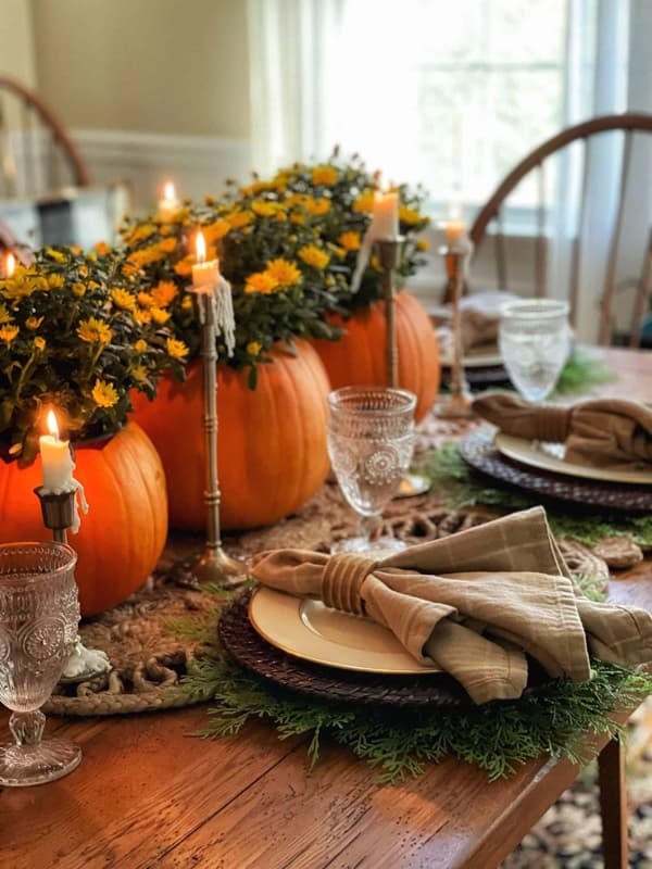 A Trio of pumpkins filled with mums and brass candles for a Thanksgiving Table Setting Idea