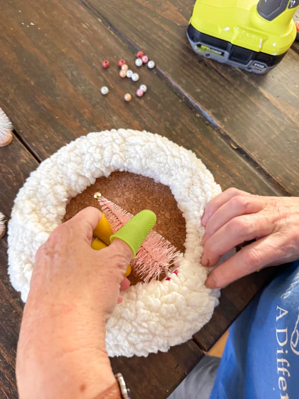 Adding pink bottle brush trees to a small dollar tree wreath wrapped in fleece fabric