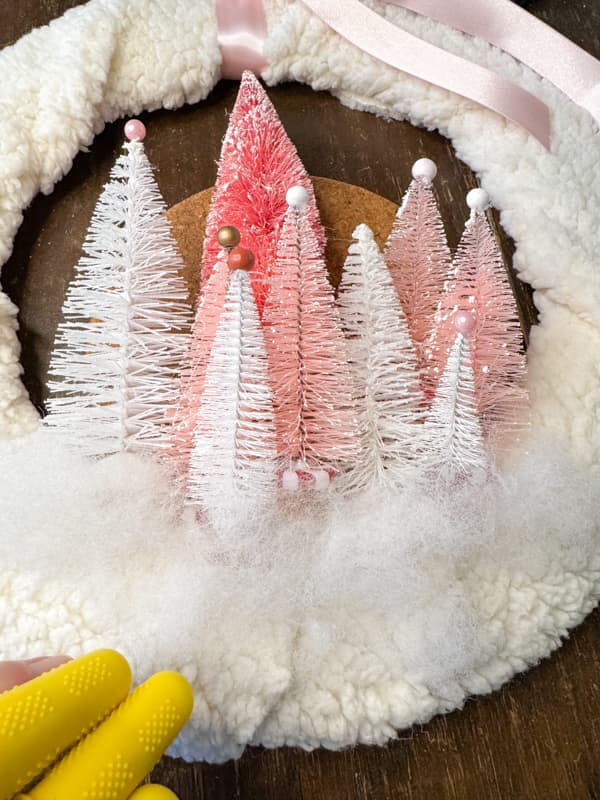 Add poly-fil to the base of the trees for a snowy effect on the Pink Christmas Wreath