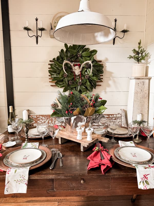 Antique Farmhouse Table set for a rustic cabin Christmas Supper Club Dinner Party with Deer Antlers.