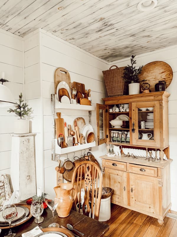 Oversized baskets and cheese board on pine hutch and DIY plate rack filled with what to look for in Thrift Stores this year.