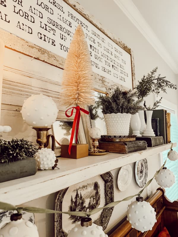 DIY hobnail milk glass ornaments decorate the mantel above the bed in the farmhouse bedroom.