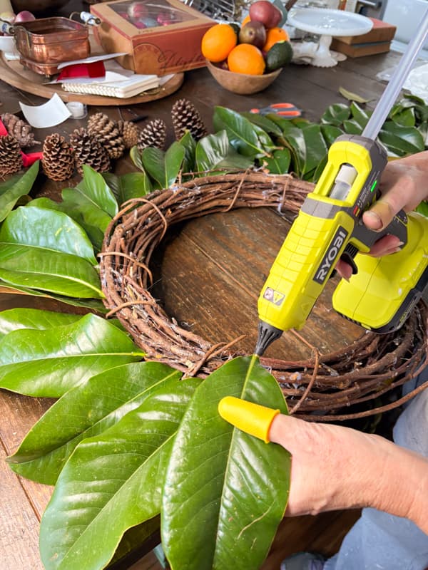 Add hot glue to stem of each magnolia leaf to assemble a Christmas Wreath