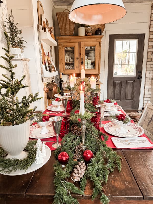 Red and white old milk glass fill a farmhouse style table for Christmas Decorating.  