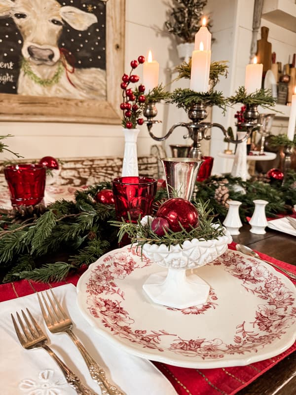 Vintage styling with milk glass for a holiday table.  Red transferware plates and silver add vintage decorations.  