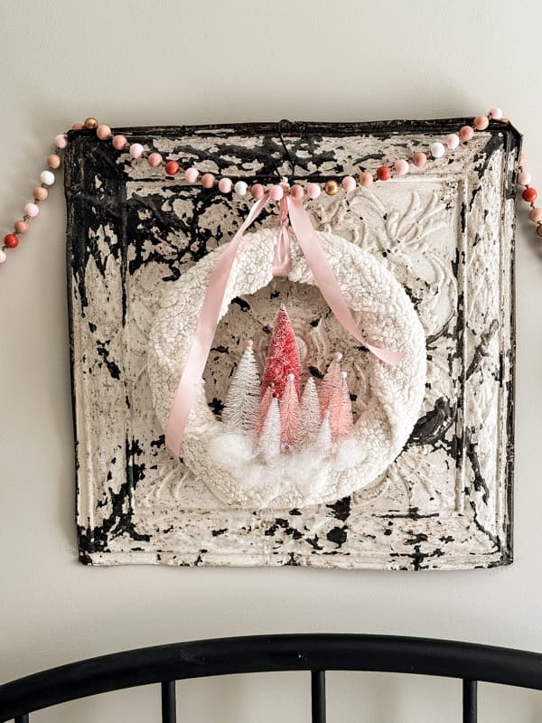 EASY and inexpensive Christmas Pink Bottle Brush Tree Wreath on a vintage ceiling tin with wooden beaded pink garland.