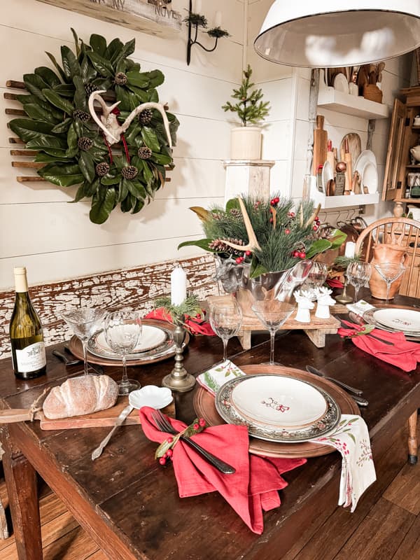 Cabin Christmas themed table with reindeer and deer antlers, magnolia &  pinecone wreath and centerpiece. 