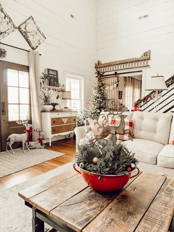 A curated home with Antique European Red and blue enamelware bowl as coffee table centerpiece with metal reindeers.  