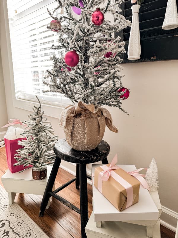 Pink Christmas Decorations with vintage shiny brite ornaments and snowy trees on a vintage foot stool