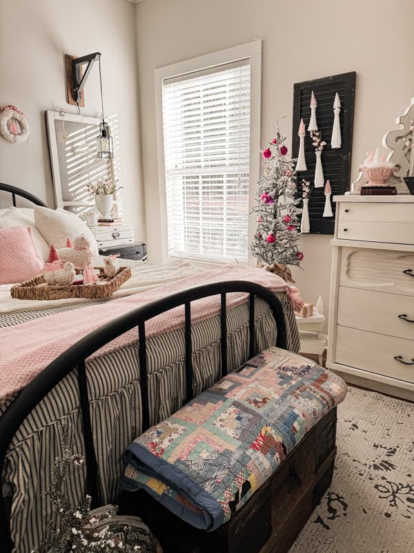 A neutral bedroom with black and white gets a pop of pink with antique quilt and vintage milk glass vases.
