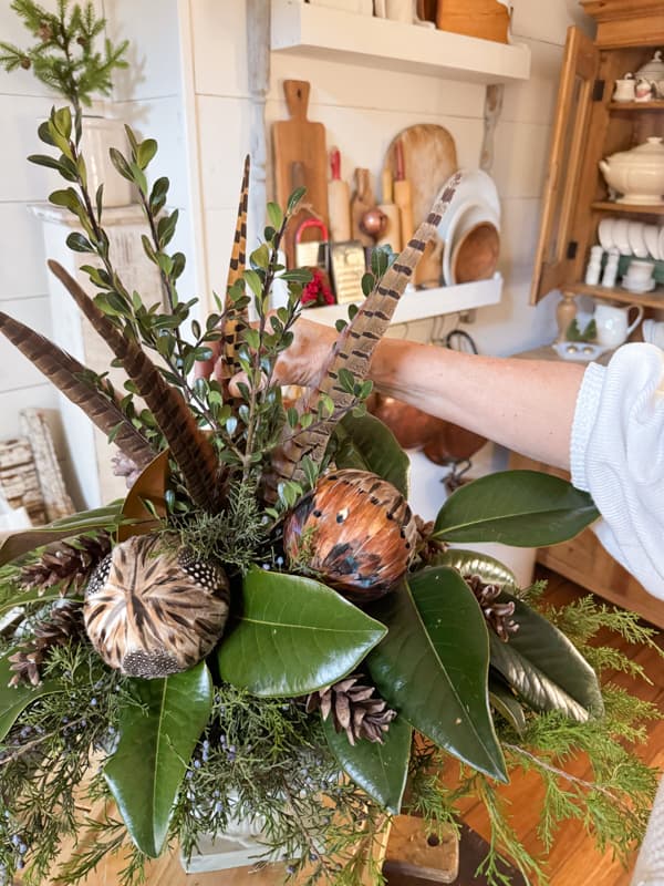 Add pheasant feathers in and around the boxwood stem for a Christmas Centerpiece idea withCedar, Magnolia and Boxwood