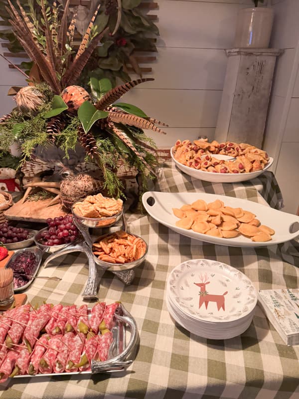 Picked okra wrapped in salami with reindeer plates on buffalo check table cloth for a Christmas Charcuterie Board Party Idea.  