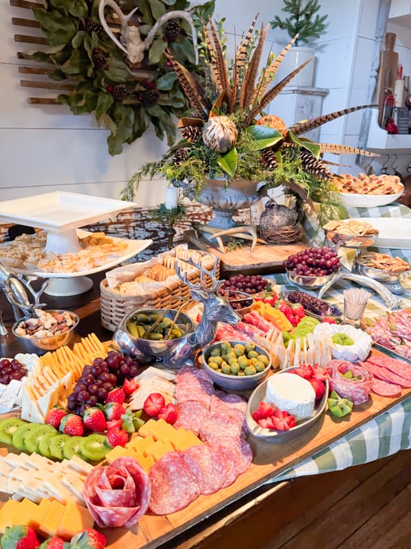 Large Charcuterie Board with Cheese, Meats, Fruit, Nuts and more.  Centerpiece fresh greenery and feathers.