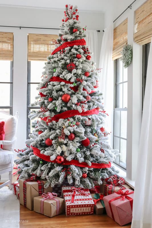 Flocked Christmas tree with red ribbon and red ornaments for budget-friendly ideas for decorating for Christmas
