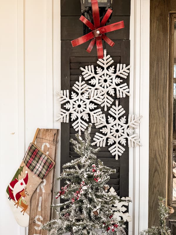 Dollar Tree Snowflakes on DIY door Shutters with red metal bow and flocked christmas tree.